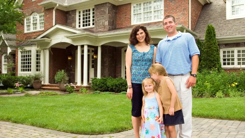 : Família feliz na frente da casa com símbolo de proteção, representando segurança com seguro incêndio
