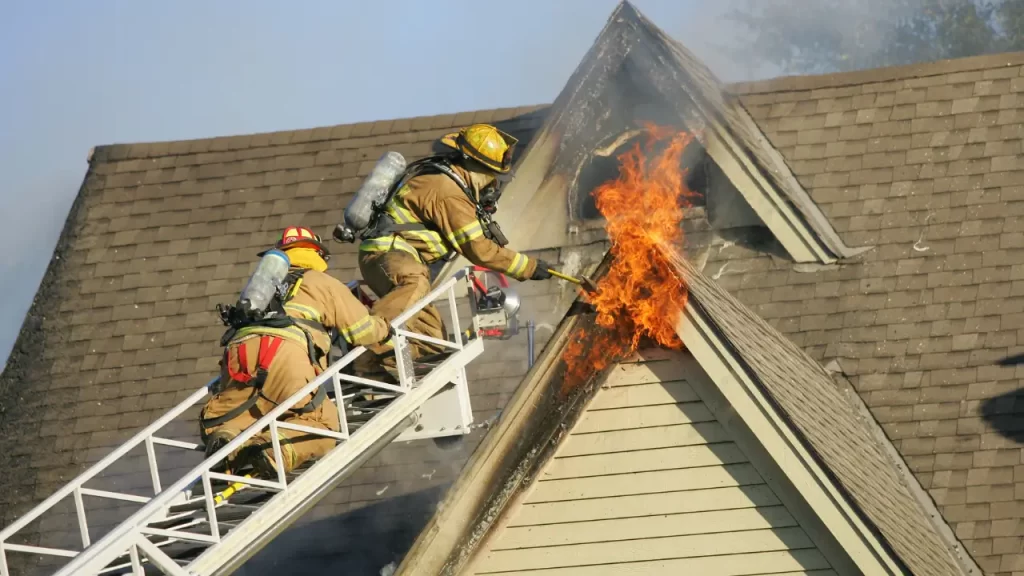 Bombeiro apagando incêndio residencial, mostrando a importância da prevenção com seguro.