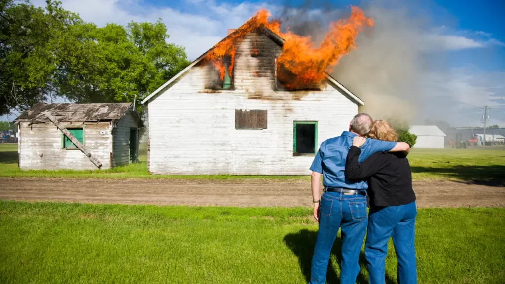 casal abraçado vendo imóvel em chamas
