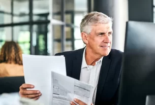 Empresário segurando documentos em ambiente de escritório, representando proteção e planejamento com seguro empresarial.
