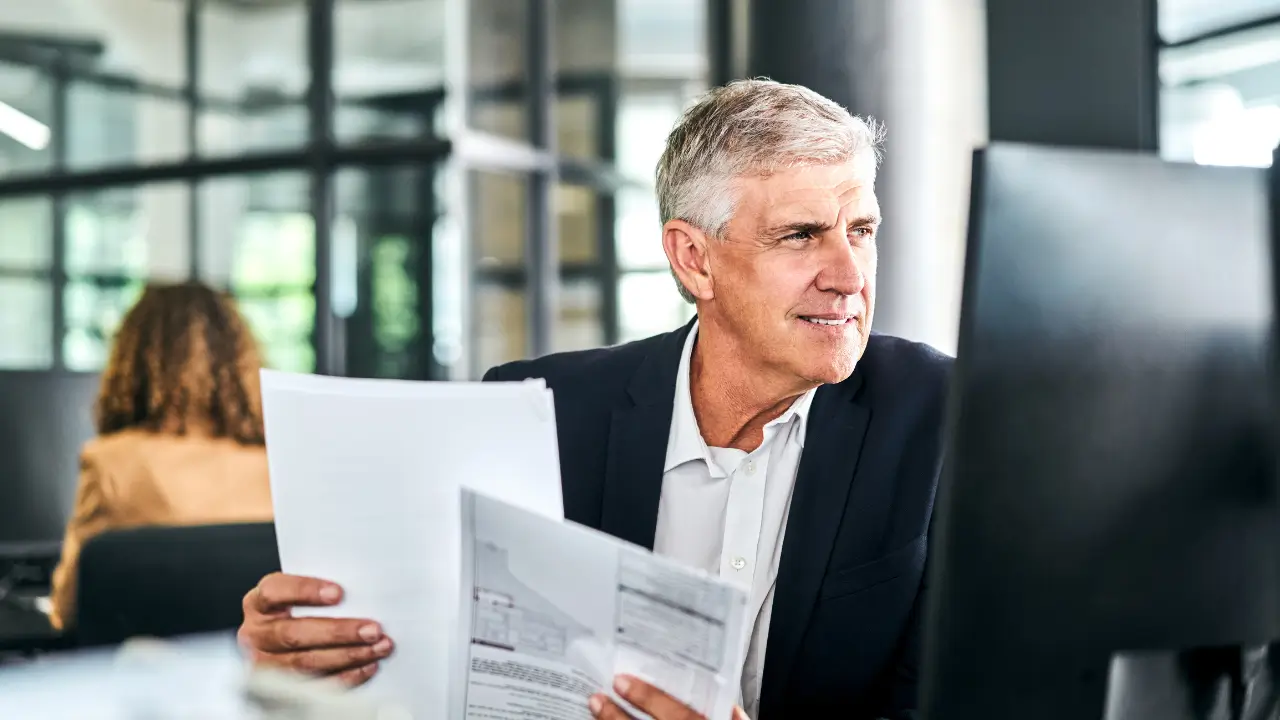 Empresário segurando documentos em ambiente de escritório, representando proteção e planejamento com seguro empresarial.