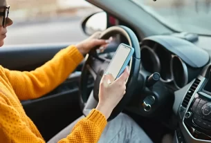 Motorista verificando seguro auto Nubank no celular dentro do carro