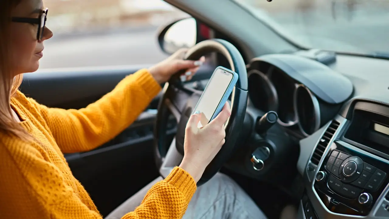 Motorista verificando seguro auto Nubank no celular dentro do carro