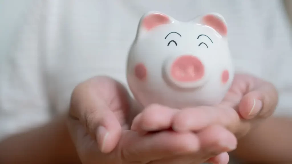 : Mãos segurando cofrinho representando planejamento financeiro com seguro prestamista.